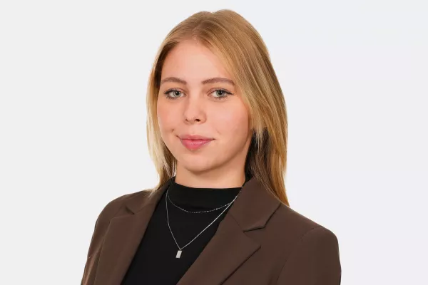 Porträt einer jungen Frau im braunen Blazer und schwarzen Oberteil vor hellem Hintergrund – professionelles Businessfoto