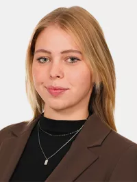 Porträt einer jungen Frau in braunem Blazer vor hellem Hintergrund.