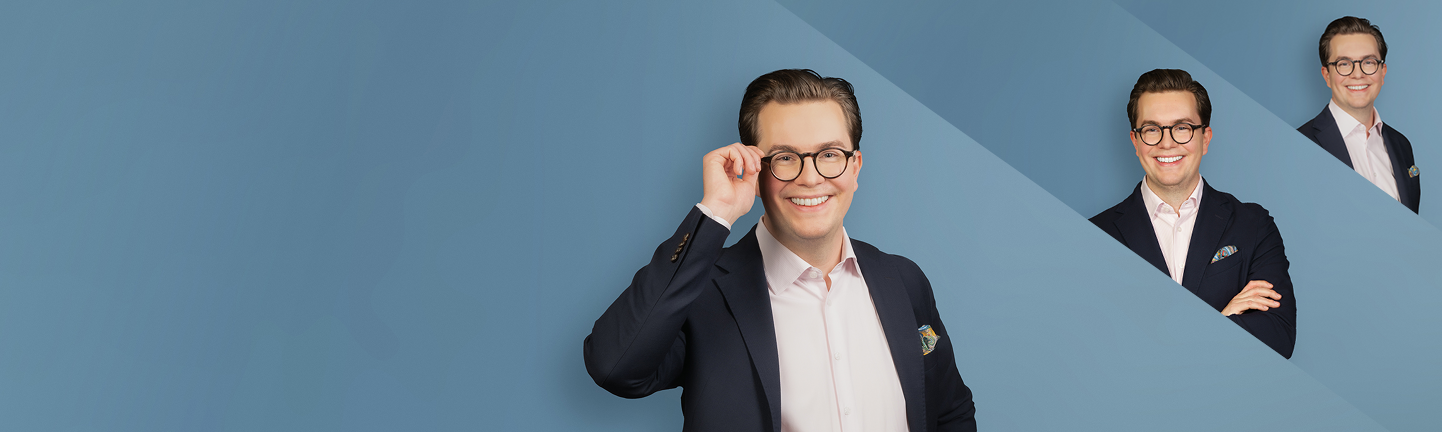 Banner mit hellblauem Verlaufshintergrund. Im Vordergrund steht eine lächelnde Person mit kurzen, zurückgekämmten Haaren und Brille. Sie trägt ein dunkelblaues Sakko über einem hellen Hemd und fasst mit einer Hand an die Brille. Rechts oben sind zwei kleinere Ausschnitte derselben Person als gestalterische Elemente eingebunden, darunter eines mit verschränkten Armen.