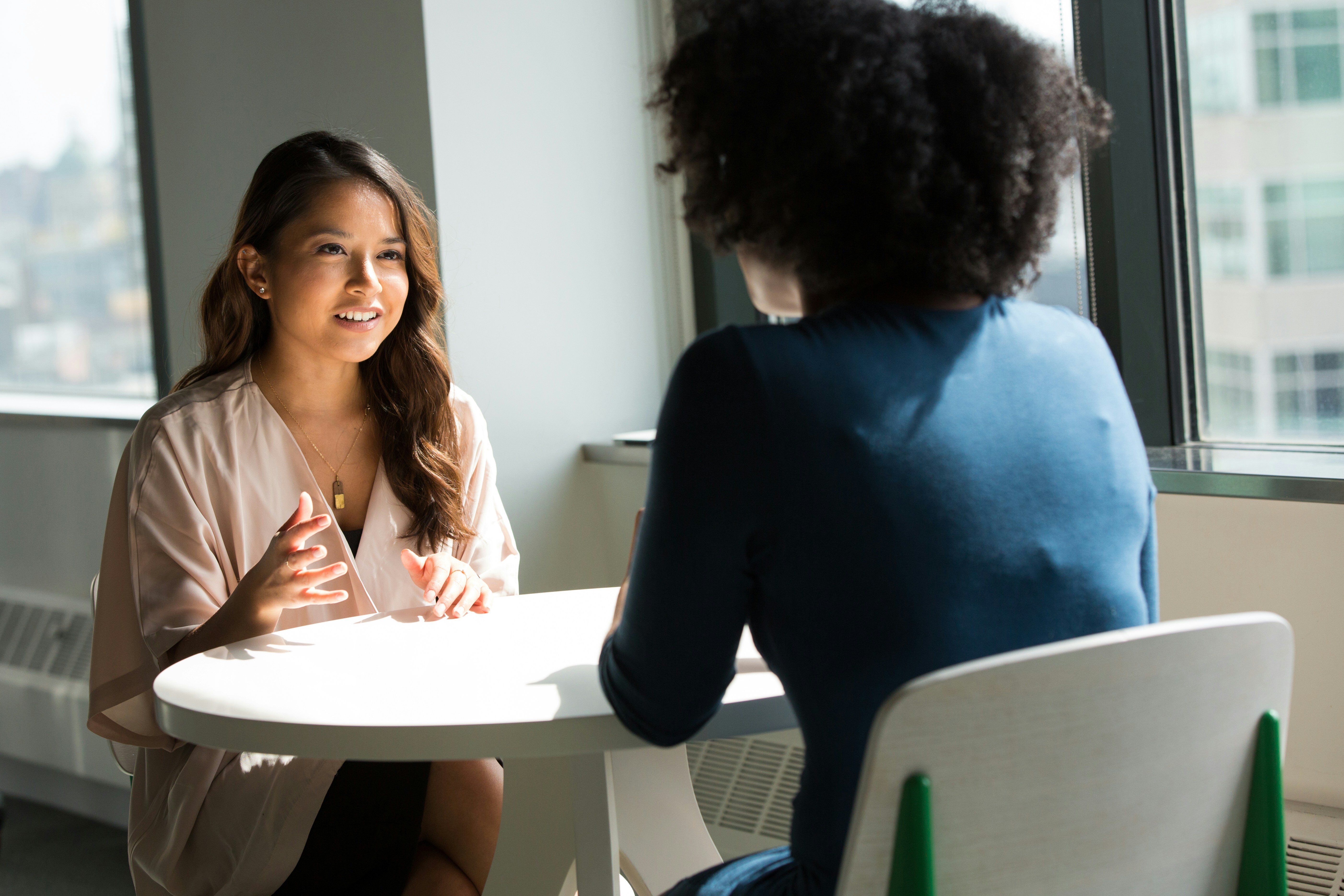 Zwei Frauen sitzen an einem Tisch und unterhalten sich.